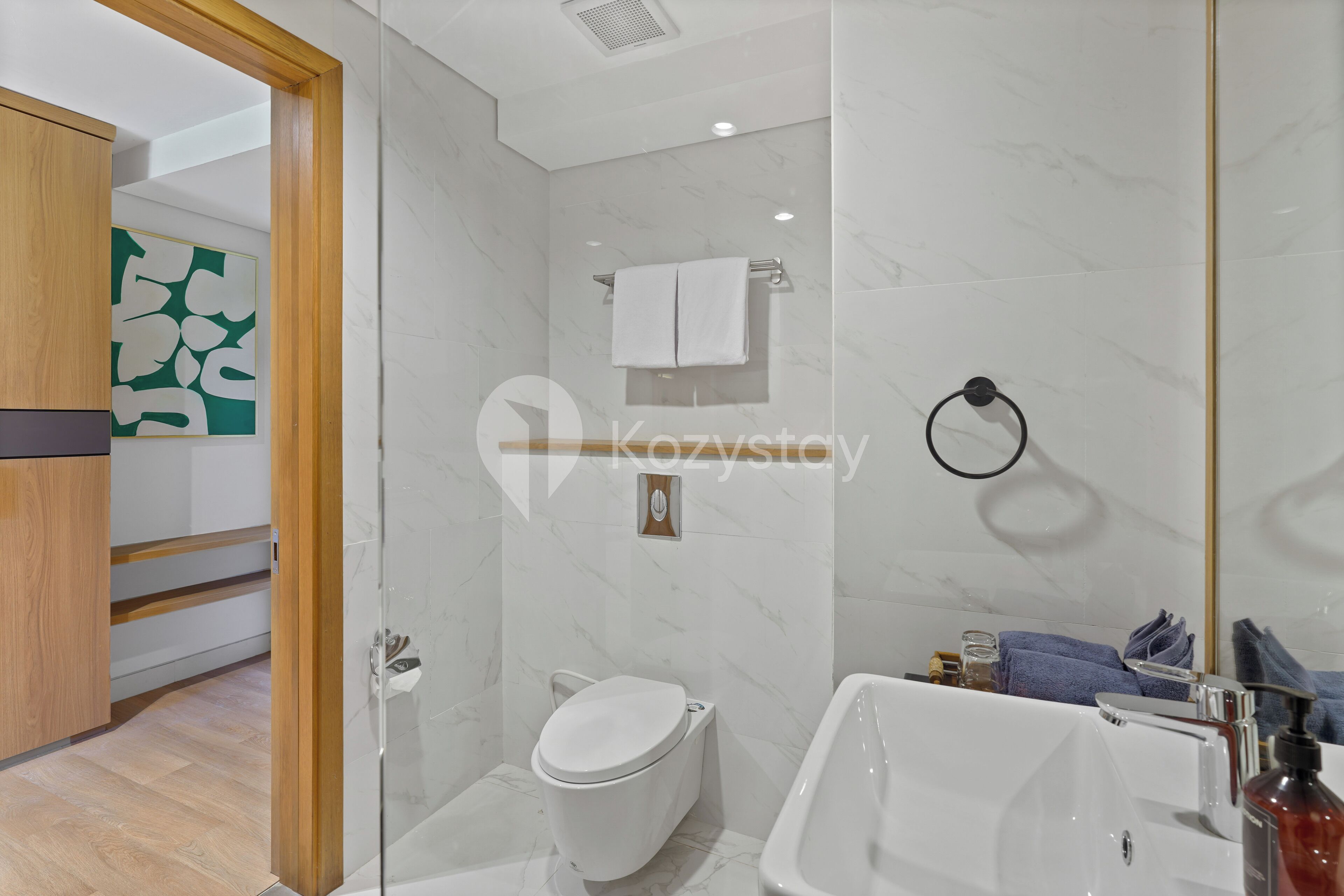 A modern bathroom with a glass shower enclosure, a white toilet, and a freestanding bathtub.