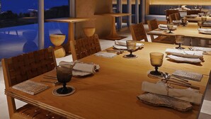 Un comedor con una mesa larga, sillas y vista al océano.