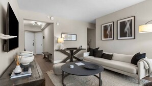 A modern living room with a sofa, coffee table, and a dining area with a table and chairs. - Elevated Minimalist Escape, Free Parking & Metro (Arlington)
