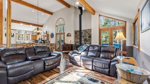 A spacious living room with leather sofas, a fireplace, and large windows. - Breckenridge Basecamp | Hot Tub + Fire Pit (Breckenridge)