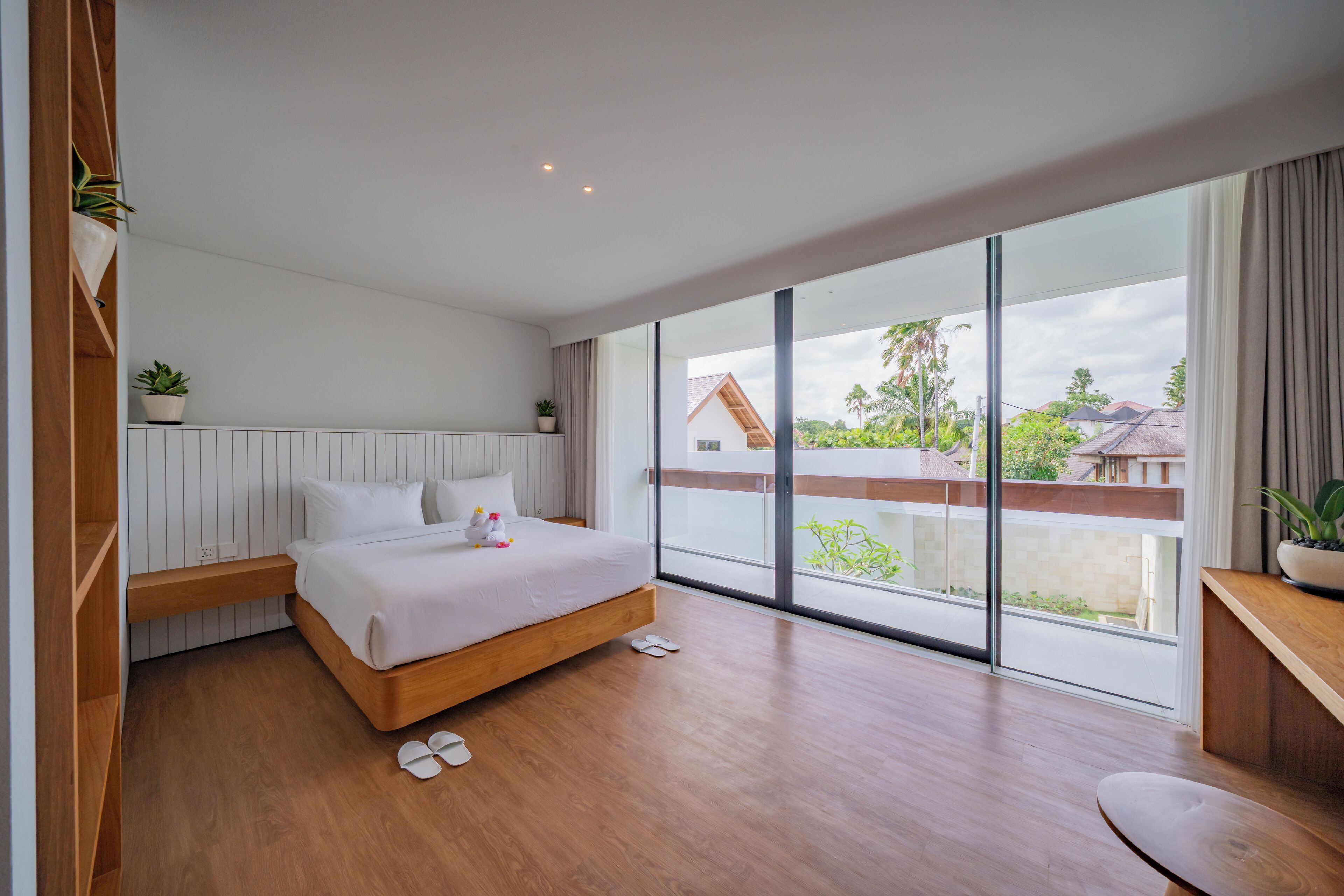 Una camera da letto moderna con un letto di legno, una grande finestra e vista su una casa.