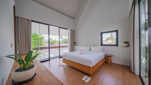 A modern bedroom with a large bed, a wooden nightstand, a potted plant, and a view of the outdoors through a sliding glass door. - Villa Shanaya Pererenan (Canggu)