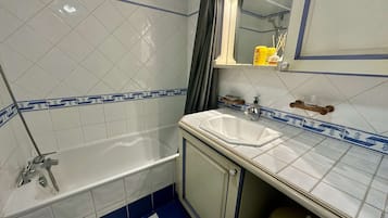 Een badkamer met een bad, wastafel en spiegel.