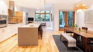 A modern kitchen with a central island, wooden flooring, and large windows. - NEW, Luxury Chalet, 5 mins to Village! (Whistler)