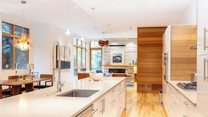 A modern kitchen with a central island, stainless steel appliances, and a wooden accent wall. - NEW, Luxury Chalet, 5 mins to Village! (Whistler)