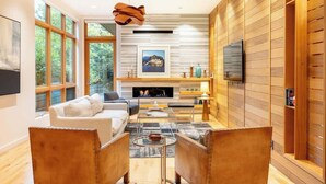 A modern living room with a fireplace, large windows, and a television. - NEW, Luxury Chalet, 5 mins to Village! (Whistler)