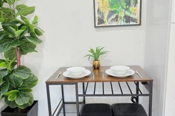 A dining table with two white plates, a pineapple, and a small potted plant.