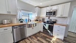 Una cucina moderna con mobili bianchi, elettrodomestici in acciaio inossidabile e pavimento in legno.