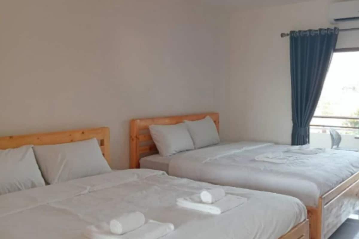 A hotel room with two wooden beds, white linens, and towels.