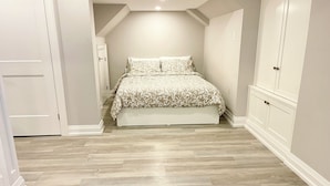 A bedroom with a bed, a wardrobe, and a wooden floor.