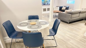 A dining area with a round table, four blue chairs, and a patterned tablecloth.