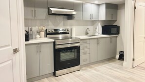 A modern kitchen with grey cabinets, stainless steel appliances, and a microwave.