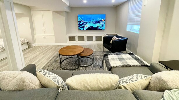 A modern living room with a flat-screen TV mounted on the wall, a sofa set, a coffee table, and a cabinet.