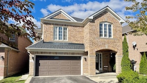 A two-story house with a brick exterior, a garage, and a well-maintained lawn.