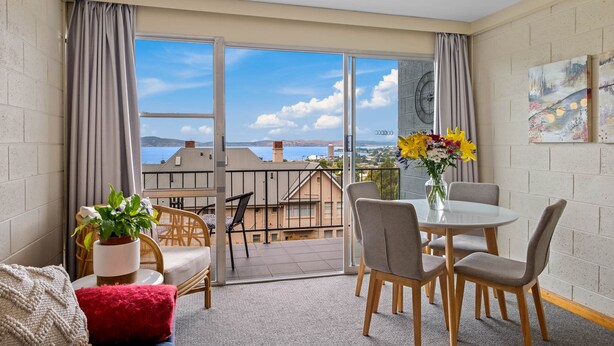 A balcony with a table and chairs, a potted plant, and a vase of flowers. - SOHO Vibes - 2 Bedroom Unit (South Hobart)