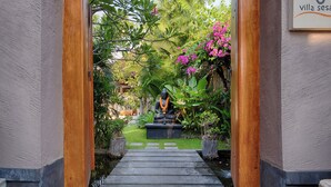 Un sentier menant à une statue dans un jardin luxuriant, avec une pancarte indiquant « Villa Sesa ».