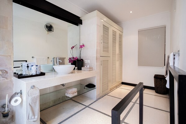 Une salle de bain moderne avec un grand miroir, un lavabo blanc et des meubles de couleur beige.