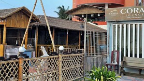 Un restaurant doté d’une clôture en bambou et d’une enseigne indiquant « Coral Lounge BBQ Restaurant ».