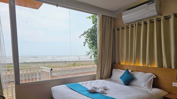 Une chambre d’hôtel dotée d’une grande fenêtre donnant sur la plage et l’océan.