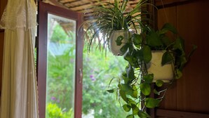 A window with a curtain, a wooden balcony, and hanging potted plants. - Mương Đình Lodge (Can Tho)