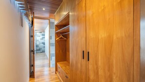A hallway with wooden flooring and a large wardrobe with multiple drawers and hanging space.