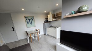 Una cocina moderna con armarios blancos, horno empotrado y comedor con mesa y sillas de vidrio.