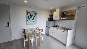 Una cocina moderna con armarios blancos, una mesa de comedor de cristal y una obra de arte con temática de mariposas en la pared.