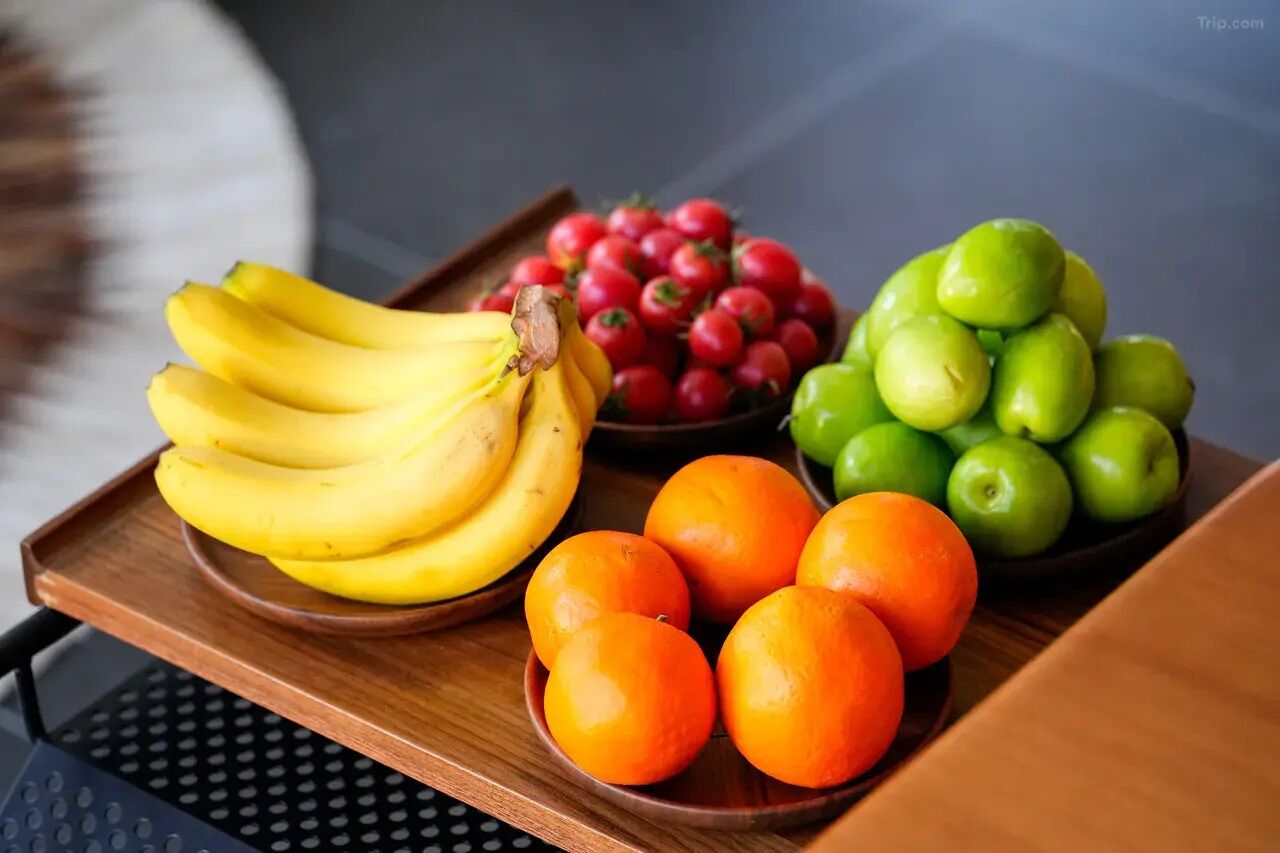 A tray with bananas, cherries, oranges, and green apples.