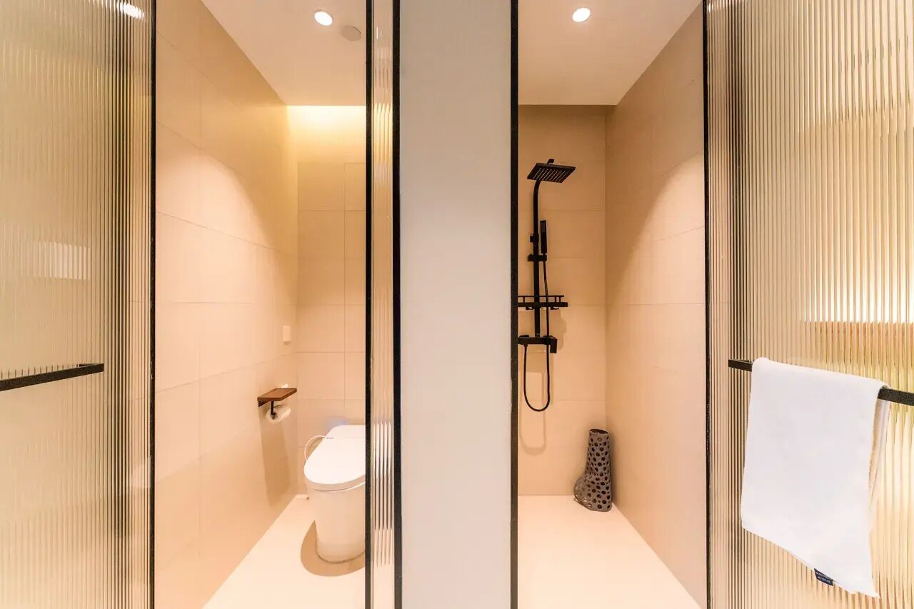 A modern bathroom with a glass partition, a shower, a toilet, and a towel rack.