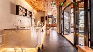 Ein modernes Interieur mit Holzbalkendecke, einer Bar mit Regalen und einer Sitzecke mit Blick.