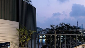 A balcony with a washing machine, a wicker table, a wicker chair, and a potted plant. - Home. Homestay (Hanoi)