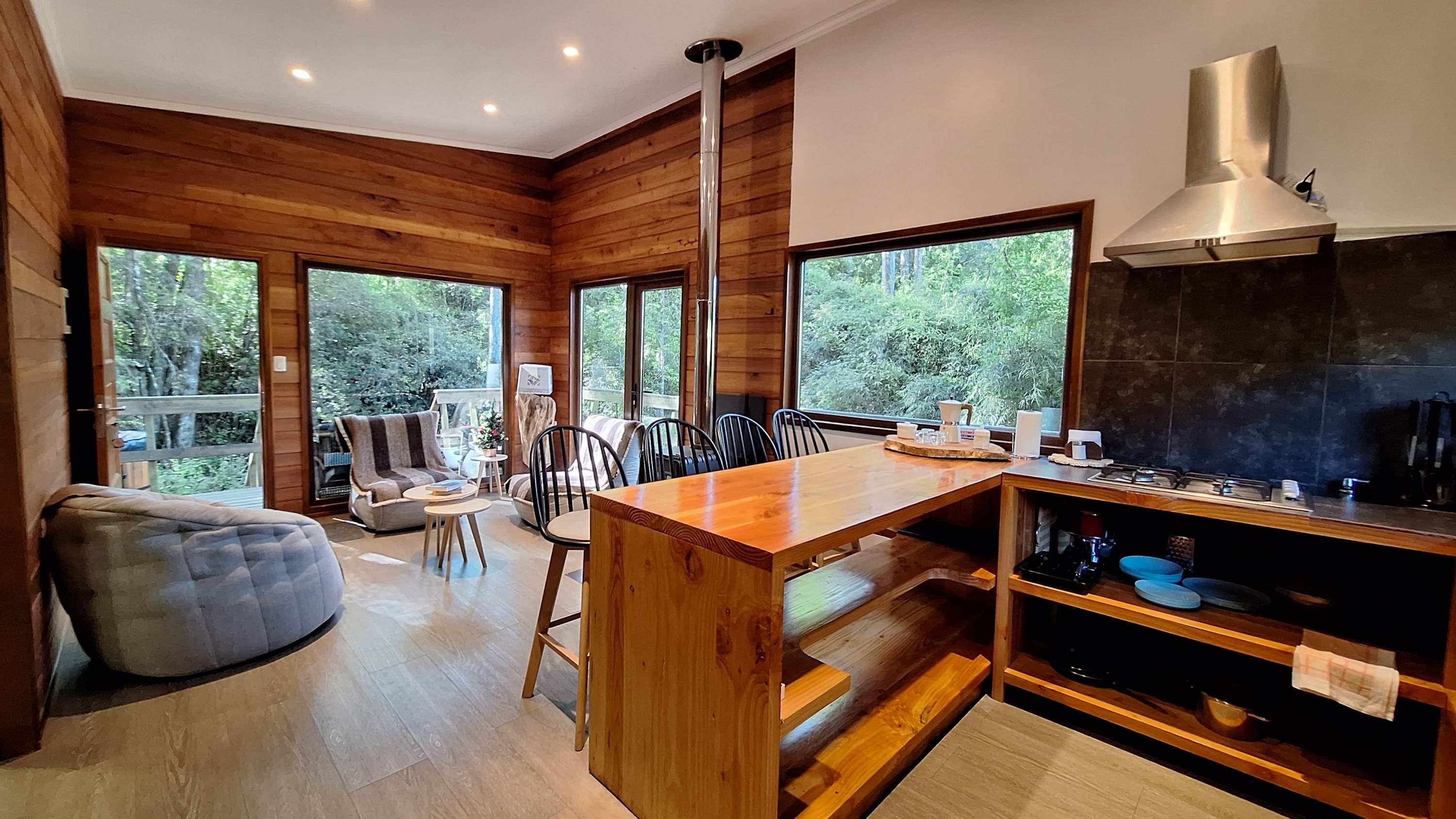 A modern kitchen with wooden walls, large windows, and a central island.