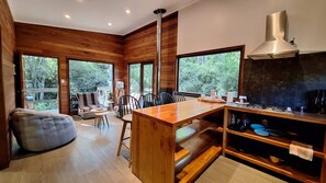 Eine moderne Küche mit Holzwänden, großen Fenstern und einer zentralen Kochinsel.