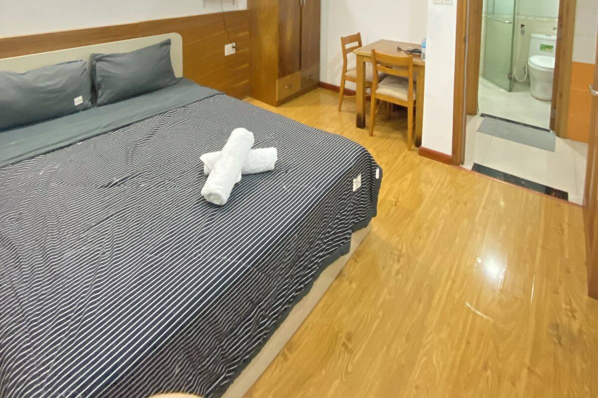 Et hotelværelse med en seng, et træskab, et skrivebord med stol og en aircondition.