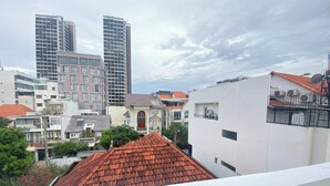 A cityscape with modern and traditional buildings, including a prominent white building with a balcony. - Uhouse - KELLY Thao Dien Apartment (Ho Chi Minh City)