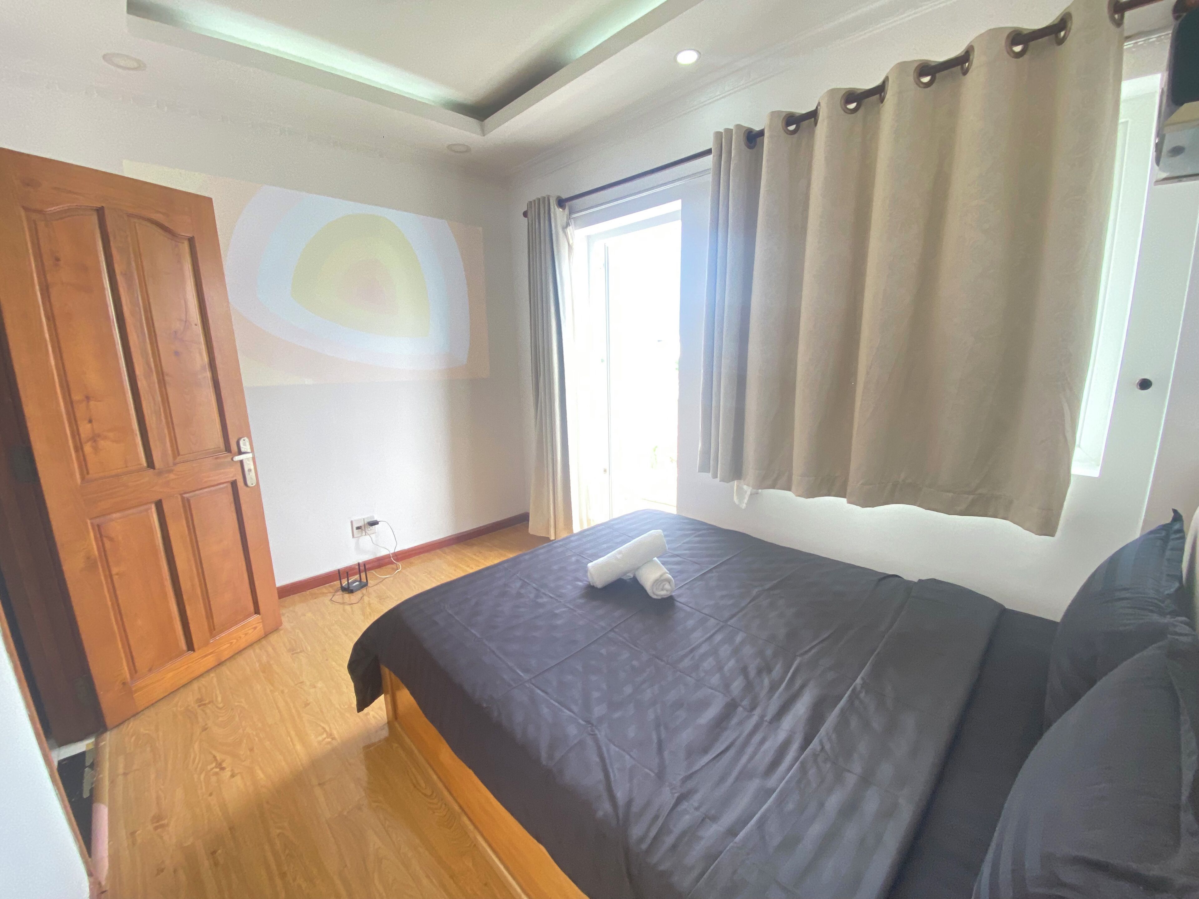 A bedroom with a bed, wooden wardrobe, and a window with curtains.