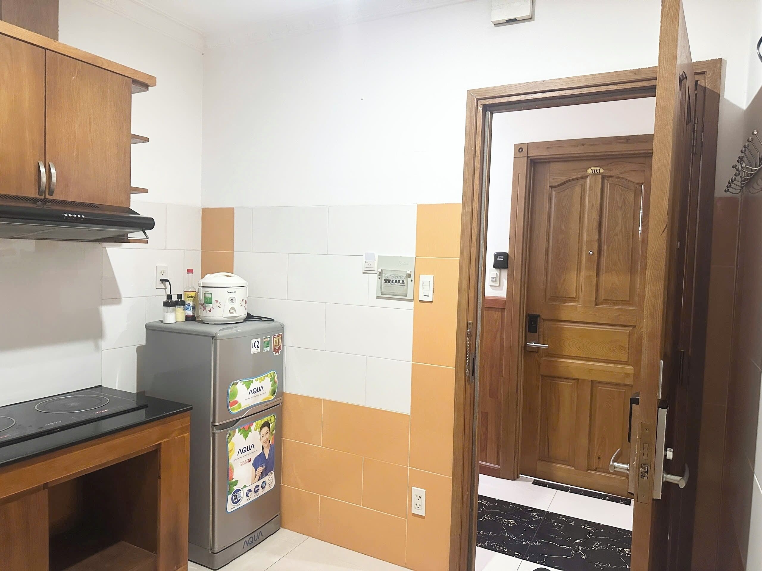 A compact kitchen with a refrigerator, a stove, and a wooden cabinet.