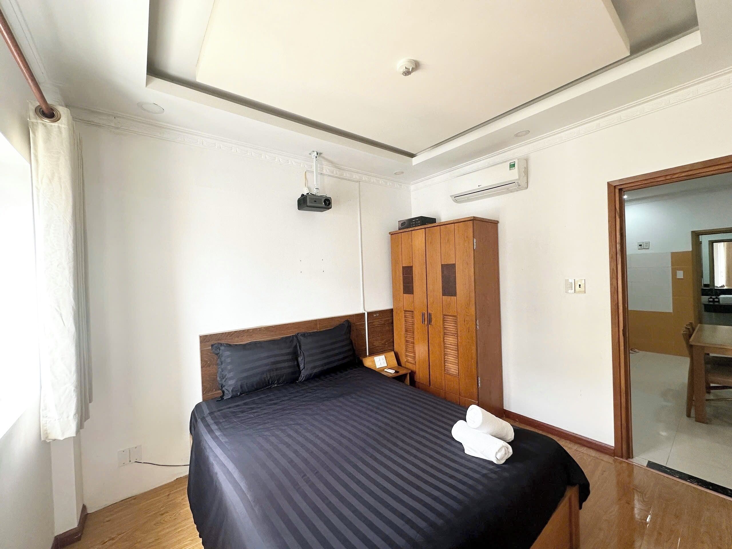 A bedroom with a bed, a wardrobe, an air conditioning unit, and a ceiling light.