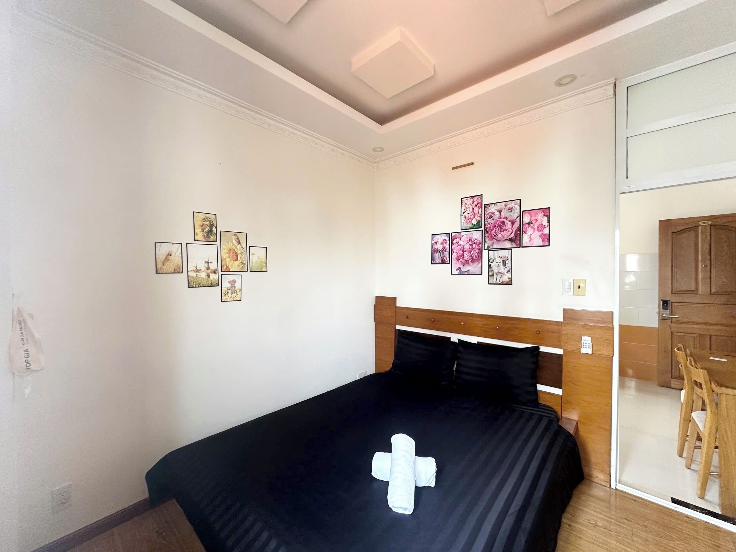A bedroom with a bed, a wooden headboard, and a wall with framed pictures.