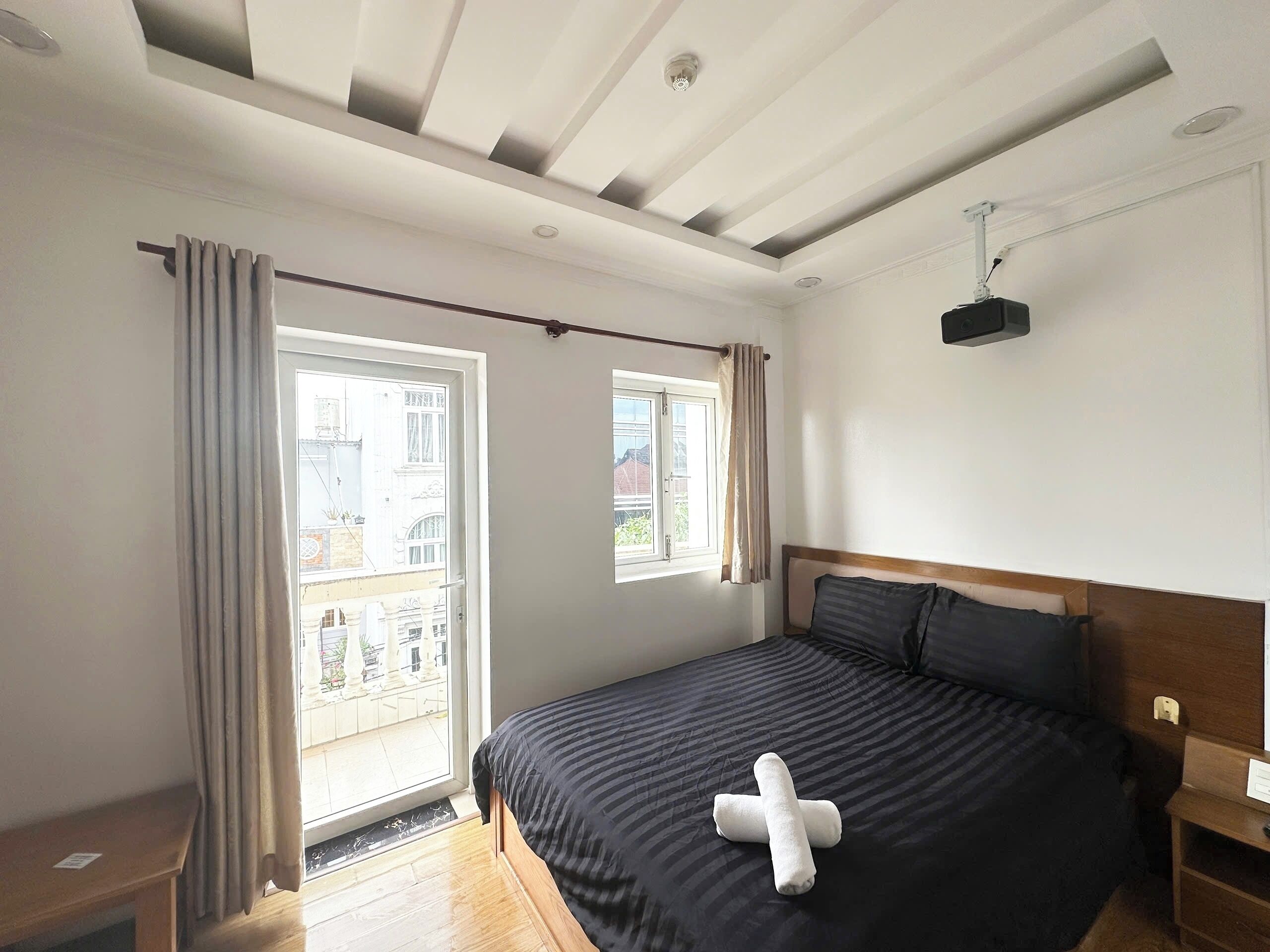 A bedroom with a bed, a nightstand, a window with curtains, and a ceiling fan.