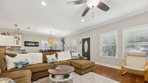 A living room with a sectional sofa, a round coffee table, and a ceiling fan.