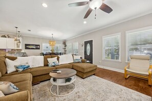 A living room with a sectional sofa, a round coffee table, and a ceiling fan.