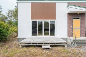 En byggnad med en vit fasad, en brun, vertikal panel och en gul dörr.