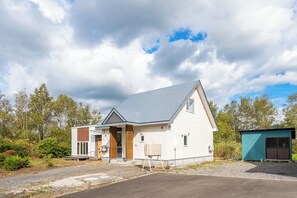 Ett modernt hus i två våningar med ett grått tak, ett litet sammanbyggt garage och en välskött gräsmatta.