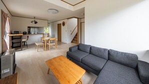 Un salon moderne avec un canapé gris, une table basse en bois et un coin repas comprenant des chaises et une table.