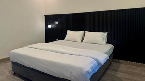 Un dormitorio moderno con una cama grande, un cabecero oscuro y una mesita de noche con lámpara.