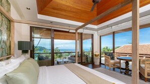 A bedroom with a large bed, a view of the outdoors, and a balcony with seating. -  Katamanda Villa Allegra 5BR Seaview villa Kata (Karon)