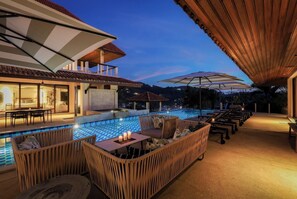 A rooftop pool area with seating and umbrellas, overlooking a cityscape at dusk. -  Katamanda Villa Allegra 5BR Seaview villa Kata (Karon)