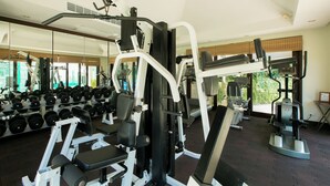 Ein Fitnessstudio mit verschiedenen Trainingsgeräten, Gewichtsständern und einer Spiegelwand.