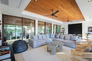 A modern living room with a sectional sofa, a black bean bag, and a patterned coffee table.